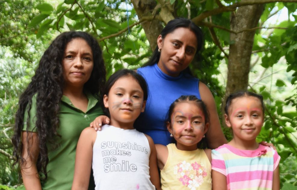 Zwei Frauen und drei Kinder stehen vor einem grünen Baum